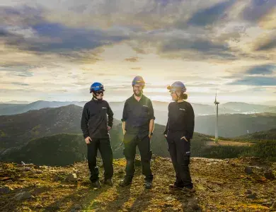 Techniciens et techniciennes face à une éolienne