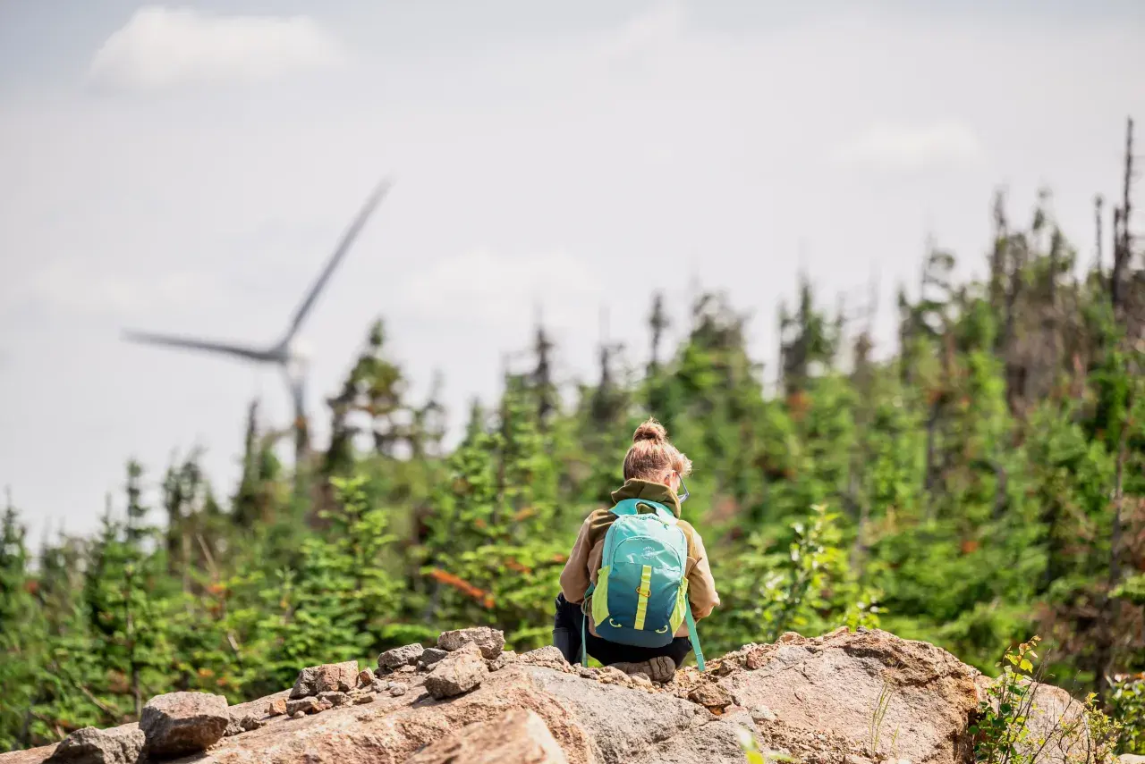Child sitting and looking at a wind turbine in Canada