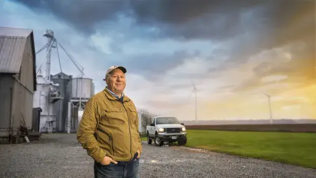 Farmer on his farm with a wind turbine in the background North America