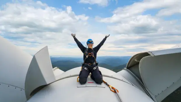 Employée sur le toit d'une éolienne levant les bras
