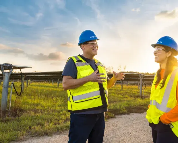 Technicien solaire discutant face à un parc solaire